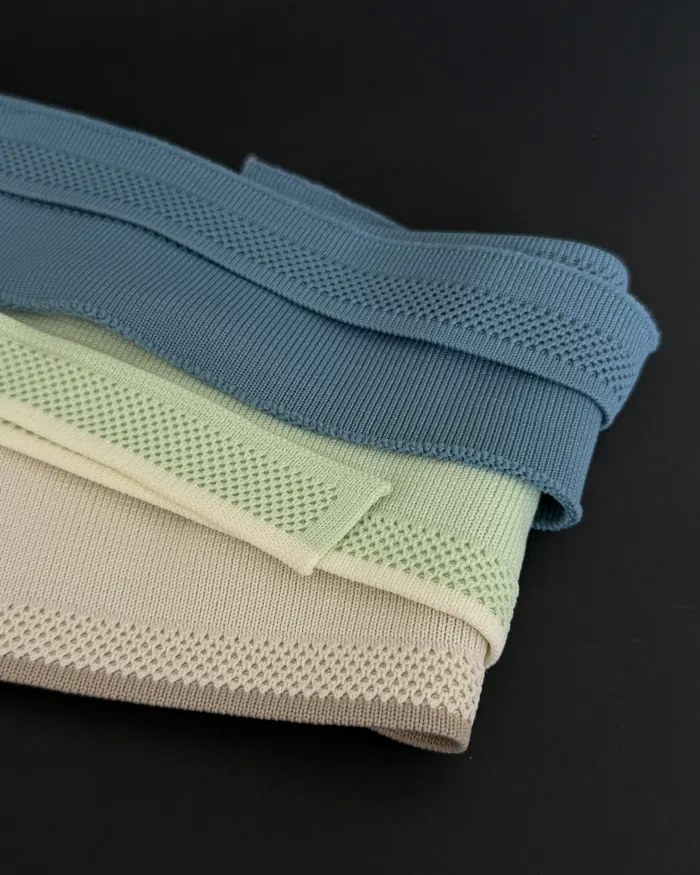 Muestras tejidas dobladas en azul, verde y marfil
